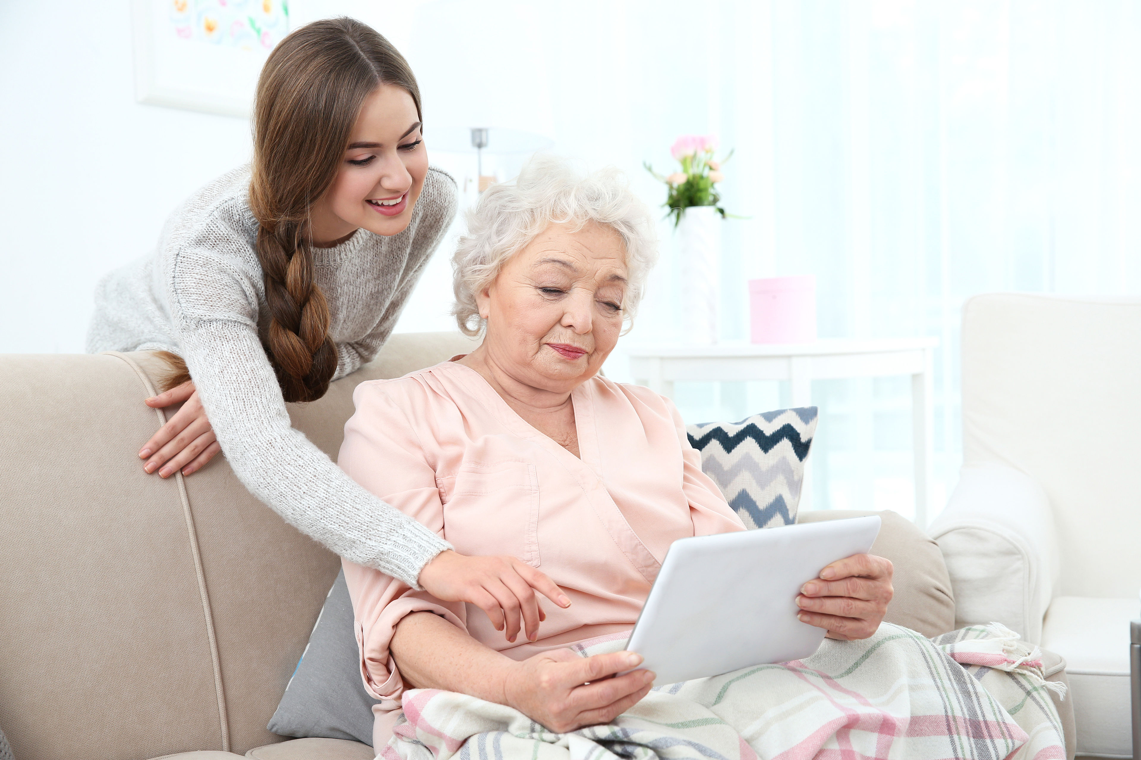 Beautiful girl with grandmother using tablet at home