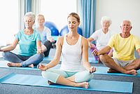 Seniorinnen und Senioren sind bei einem Yoga-Kurs