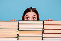 Eine Frau blickt über einen Stapel Bücher