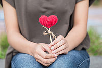 Eine Frau hält ein Herz in der Hand