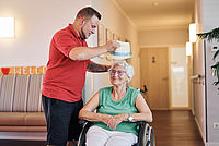 Pfleger setzt Seniorin einen Hut auf