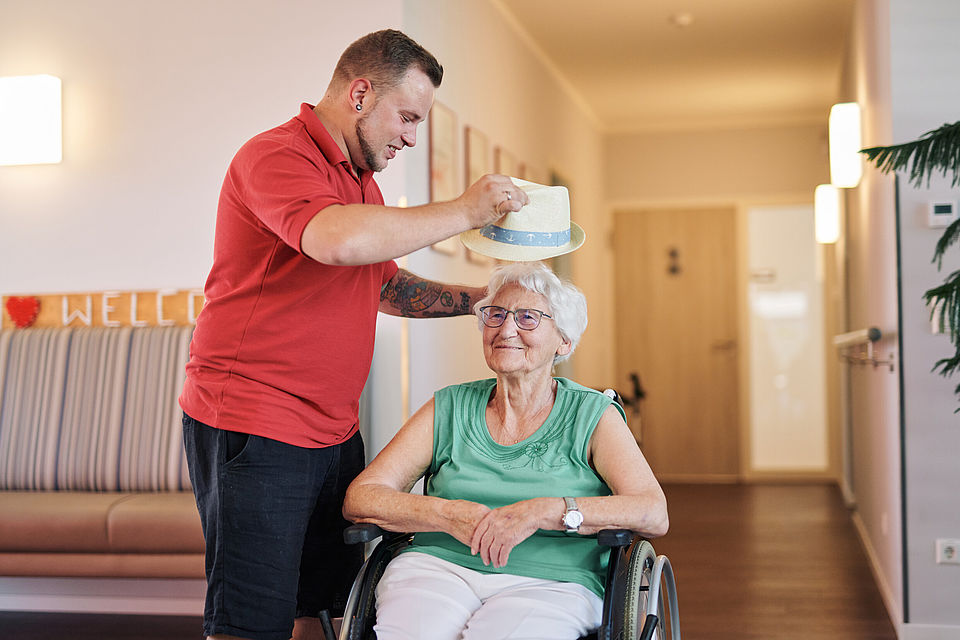 Pfleger setzt Seniorin einen Hut auf