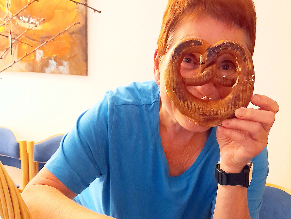 Eine Frau hält sich eine Brezel vor das Gesicht